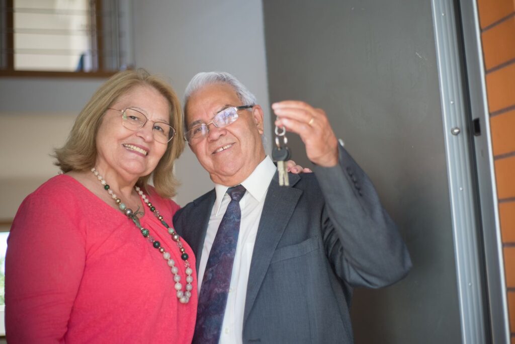 Couple de retraités tenant les clés de leur nouvelle maison à l'étranger