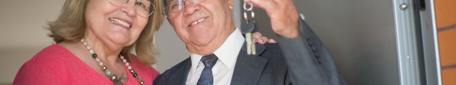 Couple de retraités tenant les clés de leur nouvelle maison à l'étranger