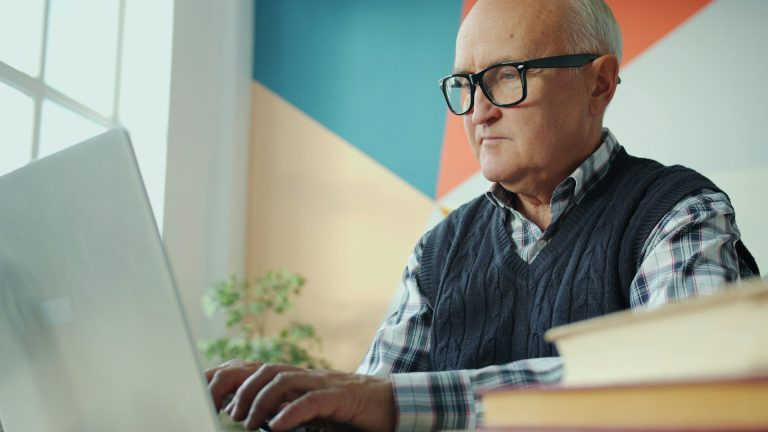 Homme âgé avec des lunettes travaillant sur un ordinateur portable