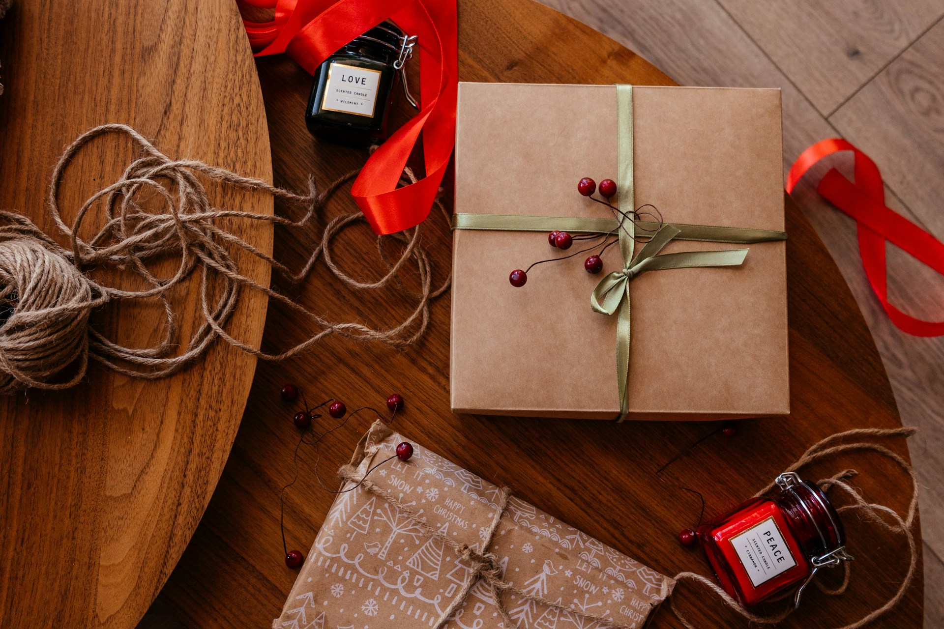 Cadeaux de Noël emballés en papier kraft avec rubans rouges sur une table en bois