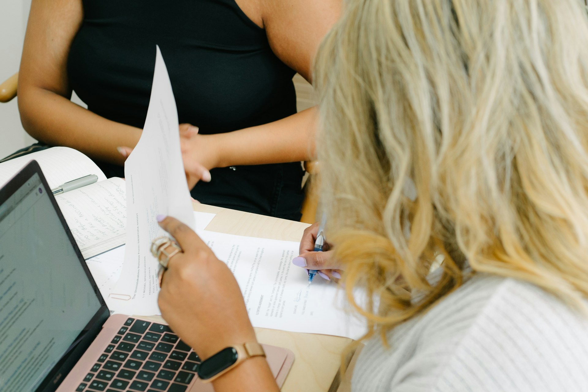 Deux personnes examinant des documents administratifs devant un ordinateur portable